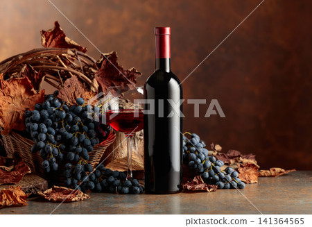 Bottle of red wine with blue grapes on a brown background. Bottle of red wine with blue grapes on a brown background. 141364565