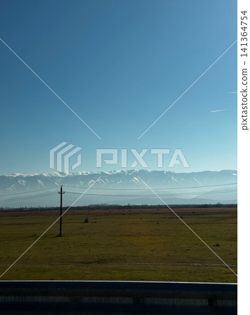 Valley plain with snow-capped Caucasus Mountains under clear sky in Georgia Valley plain with snow-capped Caucasus Mountains under clear sky in Georgia 141364754
