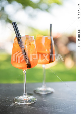 A close-up, slightly different angle of two refreshing Aperol Spritz cocktails in large wine glasses A close-up, slightly different angle of two refreshing Aperol Spritz cocktails in large wine glasses 141365706