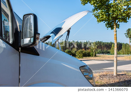 White camper van on a highway rest area with an open hood parked on a roadside for an engine check, indicating trouble or maintenance during a road trip. Copy space White camper van on a highway rest area with an open hood parked on a roadside for an engine check, indicating trouble or maintenance during a road trip. Copy space 141366070