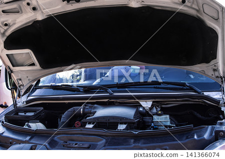 Open car hood showing engine components, vehicle maintenance, and mechanical parts. Lifted vehicle hood. Automotive repair concept with a detailed engine bay view 141366074