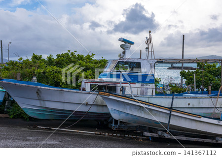 Japanese fishing boats and small speedboats moored at the tranquil fishing port pier Japanese fishing boats and small speedboats moored at the tranquil fishing port pier 141367112