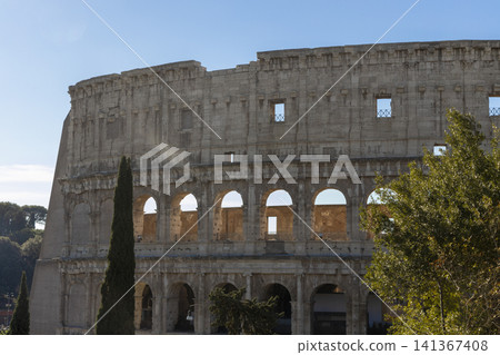 Famous Coliseum in Rome. Colosseum, or Coliseum. Part of the wall of an antique stone structure with arches. Italy, Europe. Famous touristic place in the world, Europe. Beautiful blue sky background. Famous Coliseum in Rome. Colosseum, or Coliseum. Part of the wall of an antique stone structure with arches. Italy, Europe. Famous touristic place in the world, Europe. Beautiful blue sky background. 141367408