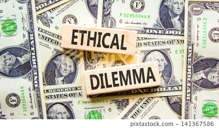 Ethical dilemma words symbol. Concept words Ethical dilemma on beautiful wooden blocks. Beautiful dollar bills background. Dollar bills. Business and Ethical dilemma words concept. Copy space. Ethical dilemma words symbol. Concept words Ethical dilemma on beautiful wooden blocks. Beautiful dollar bills background. Dollar bills. Business and Ethical dilemma words concept. Copy space. 141367586