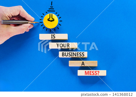Is your business a mess symbol. Concept words Is your business a mess on beautiful wooden blocks. Beautiful blue background. Businessman hand. Light bulb. Is your business a mess concept. Copy space. 141368012