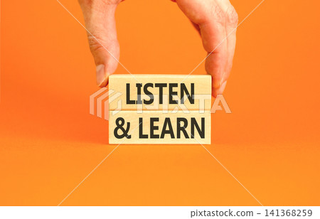 Listen and learn words symbol. Concept words Listen and learn on beautiful wooden blocks. Beautiful orange background. Businessman hand. Business listen and learn support concept. Copy space. 141368259