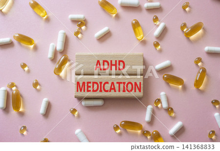 ADHD medication symbol. Concept word ADHD medication on wooden blocks. Beautiful pink background with pills. Medicine and ADHD medication. Copy space ADHD medication symbol. Concept word ADHD medication on wooden blocks. Beautiful pink background with pills. Medicine and ADHD medication. Copy space 141368833