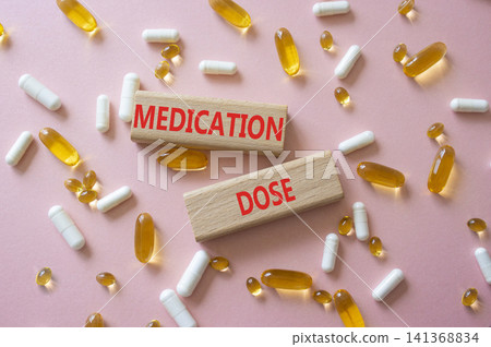 Medication dose symbol. Concept word Medication dose on wooden blocks. Beautiful pink background with pills. Medicine and Medication dose. Copy space Medication dose symbol. Concept word Medication dose on wooden blocks. Beautiful pink background with pills. Medicine and Medication dose. Copy space 141368834