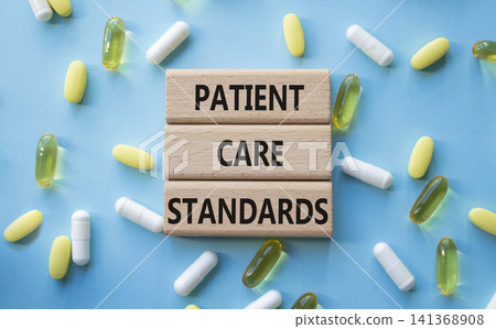 PATIENT CARE STANDARDS symbol. Concept words PATIENT CARE STANDARDS on wooden blocks. Beautiful blue background with pills. Healthcare and PATIENT CARE STANDARDS concept. Copy space. PATIENT CARE STANDARDS symbol. Concept words PATIENT CARE STANDARDS on wooden blocks. Beautiful blue background with pills. Healthcare and PATIENT CARE STANDARDS concept. Copy space. 141368908
