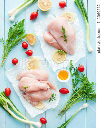 Fresh raw chicken breast meat on parchment paper with greens, healthy vegetables and fruits Fresh raw chicken breast meat on parchment paper with greens, healthy vegetables and fruits 141369212