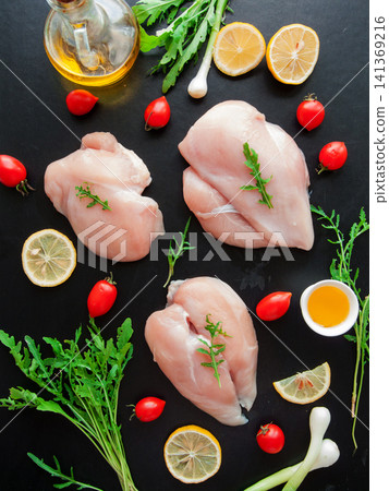 Fresh raw chicken breast meat with greens, fresh cherry tomatoes and lemon slices preparing to cook Fresh raw chicken breast meat with greens, fresh cherry tomatoes and lemon slices preparing to cook 141369216