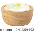 Creamy white yogurt with yellow fruit chunks served in a small round wooden bowl isolated. Healthy dairy product, breakfast snack, or cooking ingredient concept. 141369452