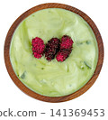 Top view of a wooden bowl filled with creamy light green avocado yogurt or pandan custard, topped with three fresh ripe mulberries. Isolated for clean food presentation. 141369453
