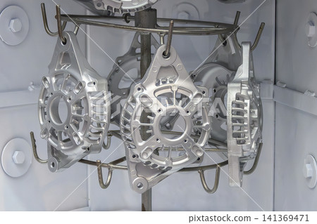 Group of aluminum alternator parts inside a chamber room prepared for a sandblasting process. Group of aluminum alternator parts inside a chamber room prepared for a sandblasting process. 141369471