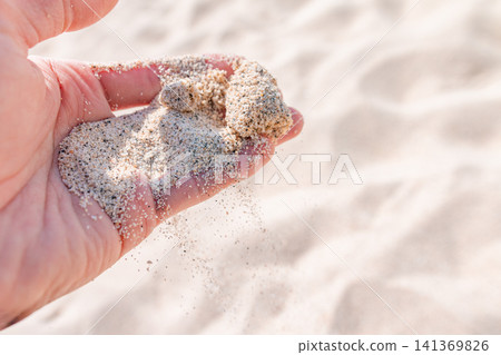 沙灘上,白色的沙子從我的掌心滑落。 沙灘上,白色的沙子從我的掌心滑落。 141369826