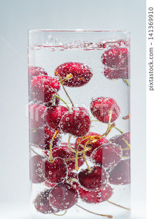 Cherries floating in carbonated water, covered in lots of bubbles. 141369910