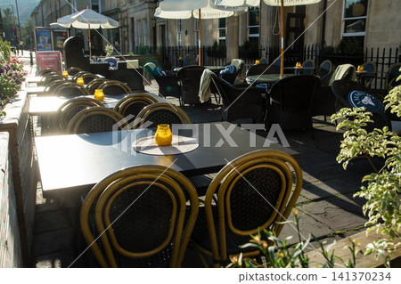 Chairs and tables lined up in front of a shop under the morning sun - the streets of Bath, a UNESCO World Heritage site in the UK. Chairs and tables lined up in front of a shop under the morning sun - the streets of Bath, a UNESCO World Heritage site in the UK. 141370234