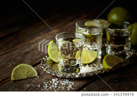 Tequila with salt and lime slices on a silver tray. 141370478
