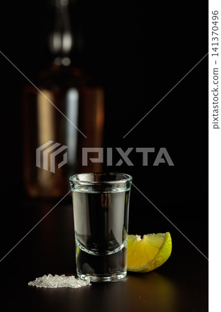 Mexican Tequila shot with lime and salt on black table. Mexican Tequila shot with lime and salt on black table. 141370496