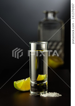 Mexican Tequila shot with lime and salt on black table. Mexican Tequila shot with lime and salt on black table. 141370497
