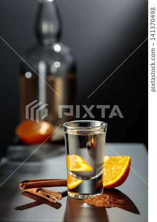 Mexican gold tequila with an orange slice and cinnamon on a black table. Mexican gold tequila with an orange slice and cinnamon on a black table. 141370498