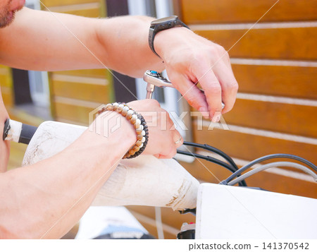 Man repairing bicycle with ratchet tool. Mechanic fixing bike components. Maintenance and service of transport. Lifestyle activity, outdoor technical work, hobby, transportation concept. Man repairing bicycle with ratchet tool. Mechanic fixing bike components. Maintenance and service of transport. Lifestyle activity, outdoor technical work, hobby, transportation concept. 141370542