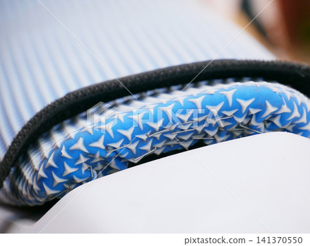 Closeup of blue patterned rubber silicone mat used for hair styling tool. Textured heat resistant accessory for curling iron or flat iron. Protective surface for hot styling equipment. Closeup of blue patterned rubber silicone mat used for hair styling tool. Textured heat resistant accessory for curling iron or flat iron. Protective surface for hot styling equipment. 141370550