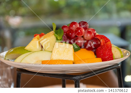 Fresh mixed fruit platter with grapes pineapple apples strawberries oranges and mint served for healthy restaurant breakfast buffet Fresh mixed fruit platter with grapes pineapple apples strawberries oranges and mint served for healthy restaurant breakfast buffet 141370612