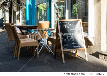 Chairs and tables lined up in front of a cafe in a back alley bathed in the morning sun – the cityscape of Bath, a UNESCO World Heritage site in the UK. Chairs and tables lined up in front of a cafe in a back alley bathed in the morning sun – the cityscape of Bath, a UNESCO World Heritage site in the UK. 141370677