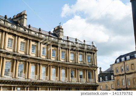 Historic honey-colored stone buildings in Bath, a UNESCO World Heritage site in the UK, bathed in bright sunlight. Historic honey-colored stone buildings in Bath, a UNESCO World Heritage site in the UK, bathed in bright sunlight. 141370782