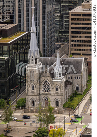 Metropolitan Cathedral of Our Lady of the Holy Rosary Cathedral surrounded by modern high-rise buildings in Downtown Vancouver British Columbia Canada. Travel photo-July 10,2022 Metropolitan Cathedral of Our Lady of the Holy Rosary Cathedral surrounded by modern high-rise buildings in Downtown Vancouver British Columbia Canada. Travel photo-July 10,2022 141370938