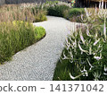 Beautiful garden pathway winding through colorful flowers and lush greenery 141371042