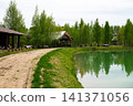 Wooden house by a lake with trees reflecting in the water during daytime in a natural setting 141371056