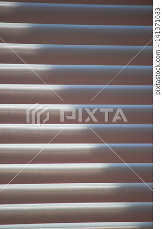 Abstract background of window blinds with sunlight filtering through the slats Abstract background of window blinds with sunlight filtering through the slats 141371083