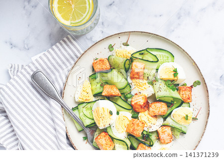 Delicious salmon and egg salad served on a plate with fresh cucumber and herbs for a healthy meal at lunchtime Delicious salmon and egg salad served on a plate with fresh cucumber and herbs for a healthy meal at lunchtime 141371239