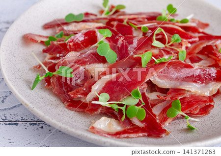 Ham of duck breast,dried duck fillet, with microgreens,plate, on a tiled table, Ham of duck breast,dried duck fillet, with microgreens,plate, on a tiled table, 141371263