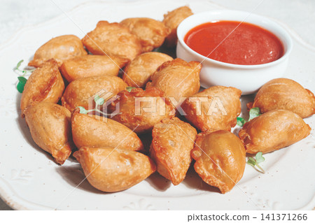 Fried mini chebureks, with sauce, on a decorative plate, hard light, no people, Fried mini chebureks, with sauce, on a decorative plate, hard light, no people, 141371266