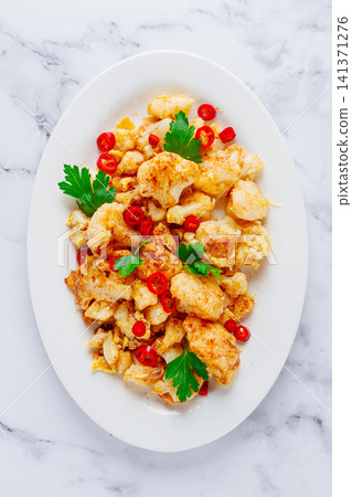 Cauliflower dish, with chili pepper and parsley, on a white plate served on a marble countertop, Cauliflower dish, with chili pepper and parsley, on a white plate served on a marble countertop, 141371276