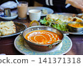 Creamy shrimp curry topped with fresh cream and naan served at the restaurant table. 141371318