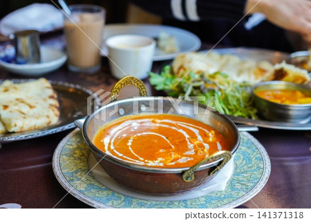 Creamy shrimp curry topped with fresh cream and naan served at the restaurant table. Creamy shrimp curry topped with fresh cream and naan served at the restaurant table. 141371318