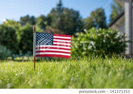 American flag in green lawn near suburban house American flag in green lawn near suburban house 141371353
