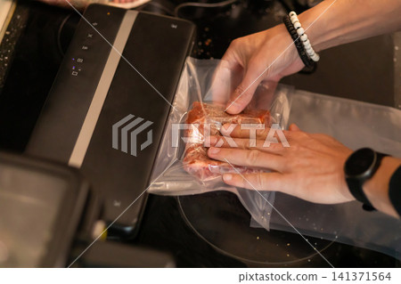 Two Hands Vacuum Sealing Marinated Pork Rib Piece in Bag 141371564