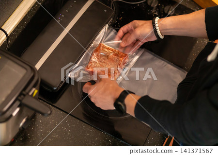 Chef Holding Vacuum Sealed Marinated Pork Rib Near Sealer 141371567