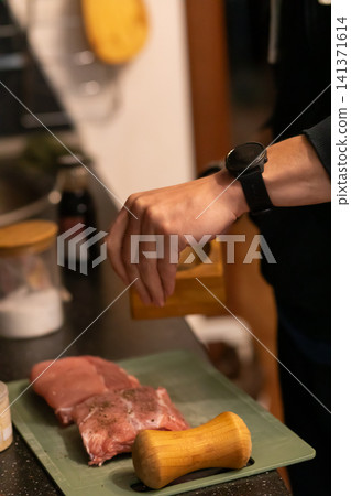 Cook Sprinkling Salt and Pepper on Raw Pork Ribs Board Cook Sprinkling Salt and Pepper on Raw Pork Ribs Board 141371614