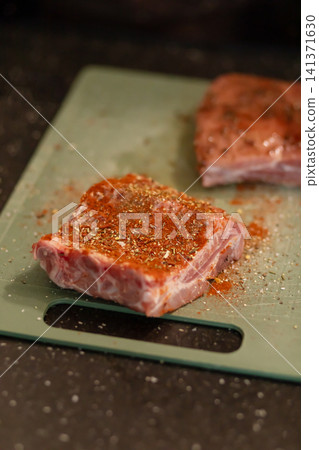 Close Up Raw Pork Rib Piece Covered in Red Paprika Rub 141371630