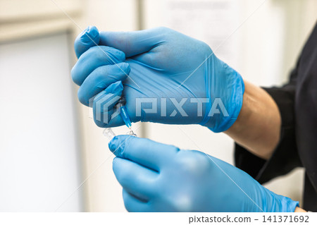 Syringe drawing medication from vial for injection 141371692