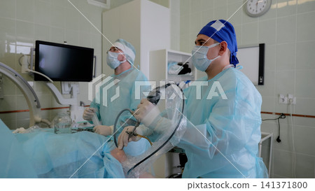 Medical team performing minimally invasive endoscopy procedure in sterile operating room with patient on table and monitors Medical team performing minimally invasive endoscopy procedure in sterile operating room with patient on table and monitors 141371800