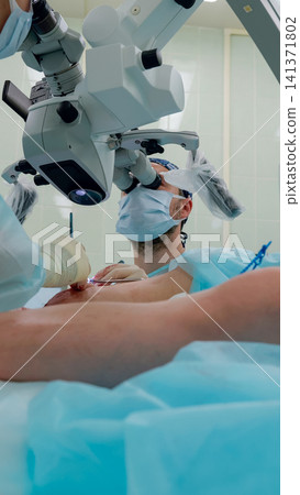 Surgeon performing microsurgical procedure using operating microscope over patient chest in sterile operating room Surgeon performing microsurgical procedure using operating microscope over patient chest in sterile operating room 141371802