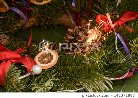 Sparkler sparks ignite an evergreen Christmas wreath, creating a serious indoor fire hazard. Sparkler sparks ignite an evergreen Christmas wreath, creating a serious indoor fire hazard. 141371998