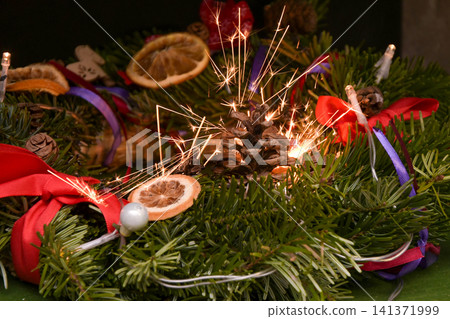 Dangerous Christmas wreath ignition from a sparkler with flying sparks Dangerous Christmas wreath ignition from a sparkler with flying sparks 141371999
